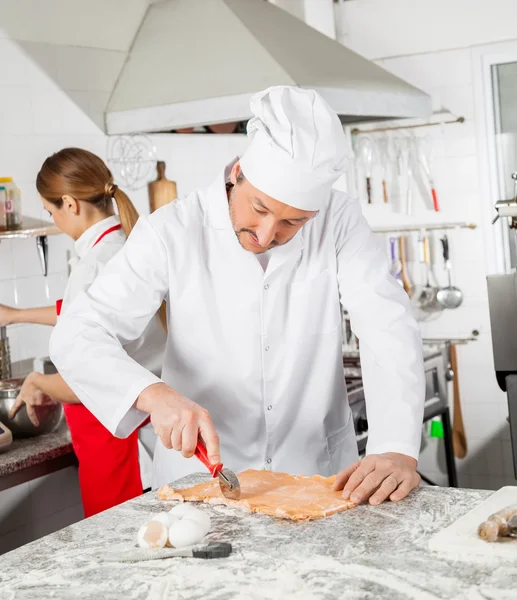 Koch schneidet Ravioli-Nudeln mit Kollegen in der Küche — Stockfoto