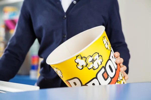 Arbetaren håller Tom Popcorn badkar på bio koncession monter — Stockfoto