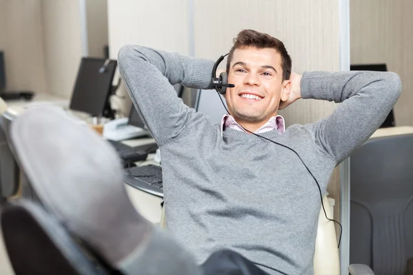 Ontspannen lachende medewerker van de klantenservice met benen op Des — Stockfoto