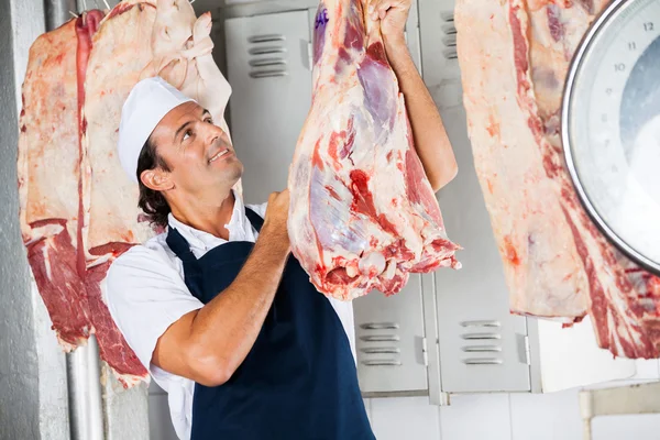 Açougueiro a olhar para a carne crua — Fotografia de Stock