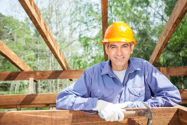 Sonriente trabajador masculino sosteniendo martillo en el sitio —  Fotos de Stock