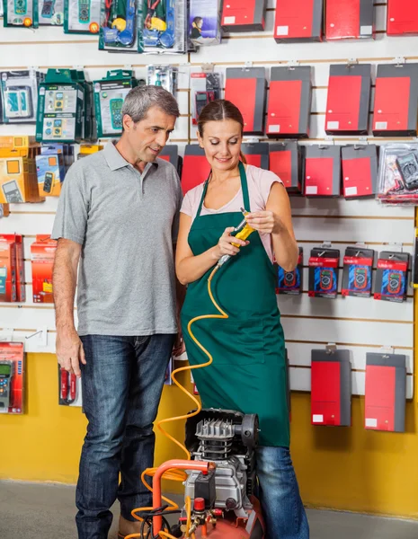 Expedit förklarar kompressor till kund i butik — Stockfoto