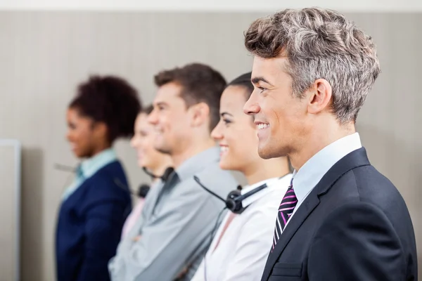 Zufriedener Manager steht in Reihe mit Callcenter-Mitarbeitern — Stockfoto