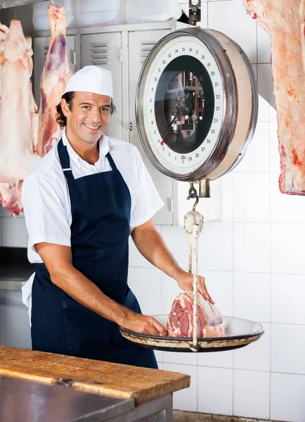 Carniceiro confiante pesando carne na balança — Fotografia de Stock