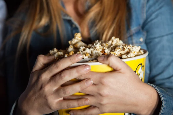 Kobieta trzyma wiadro popcornu w teatrze — Zdjęcie stockowe