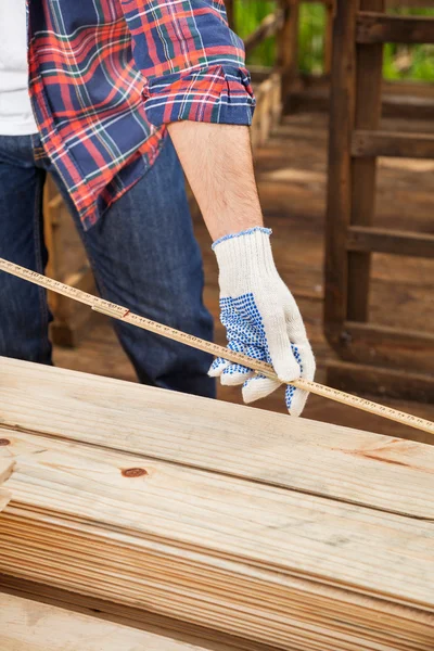 Stavební dělník měření dřeva s páskou — Stock fotografie