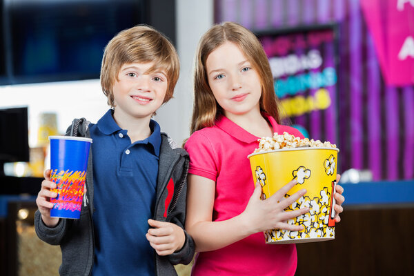 Cute Brother And Sister Holding Snacks At Cinema