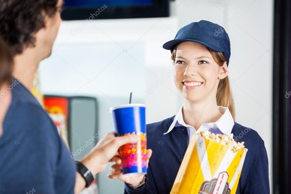 Happy Worker Selling Popcorn And Drink To Man At Cinema