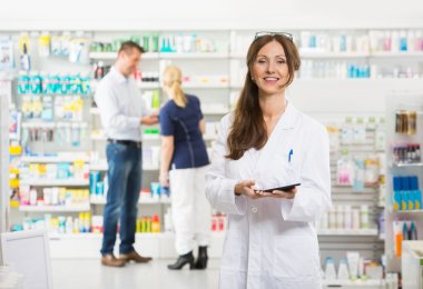 Smiling Female Chemist Holding Digital Tablet At Pharmacy