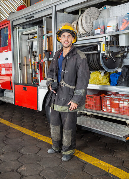 Confident Fireman Standing By Truck At Fire Station