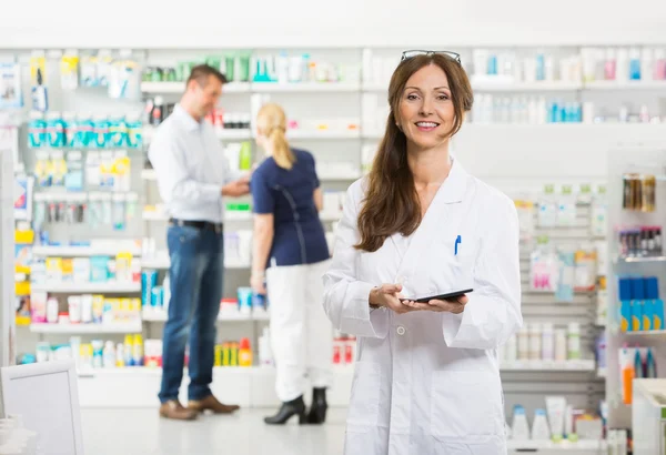 Química feminina sorridente segurando comprimido digital na farmácia — Fotografia de Stock