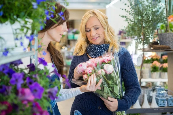 Mujer de ventas mostrando ramo de flores al cliente en la tienda — Foto de Stock