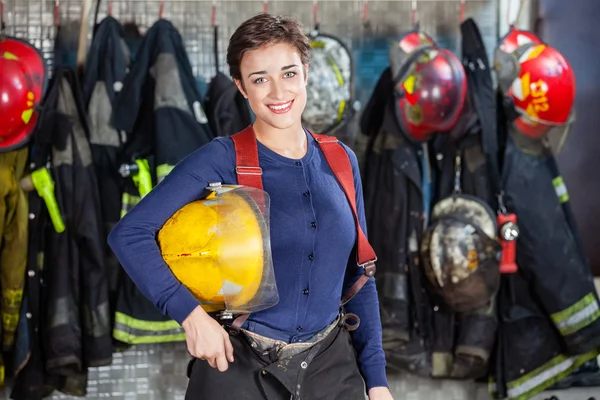 Happy Firewoman sosteniendo el casco en la estación de bomberos —  Fotos de Stock