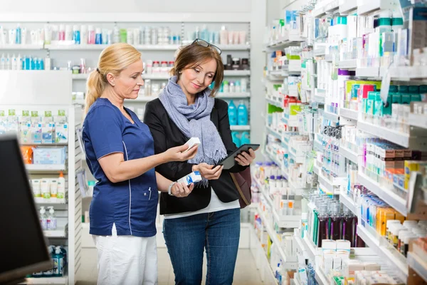 Apotheker hält Augentropfen, während Kunde digitales Tablet nutzt — Stockfoto