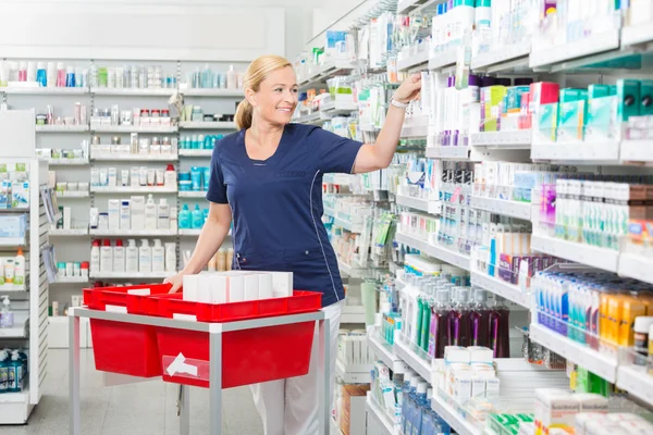 Femme souriante chimiste organiser des produits en pharmacie — Photo