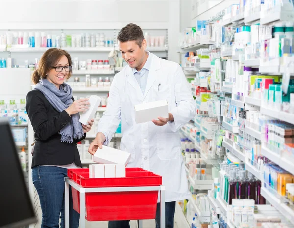 Químico masculino mostrando medicamentos para o cliente feminino — Fotografia de Stock