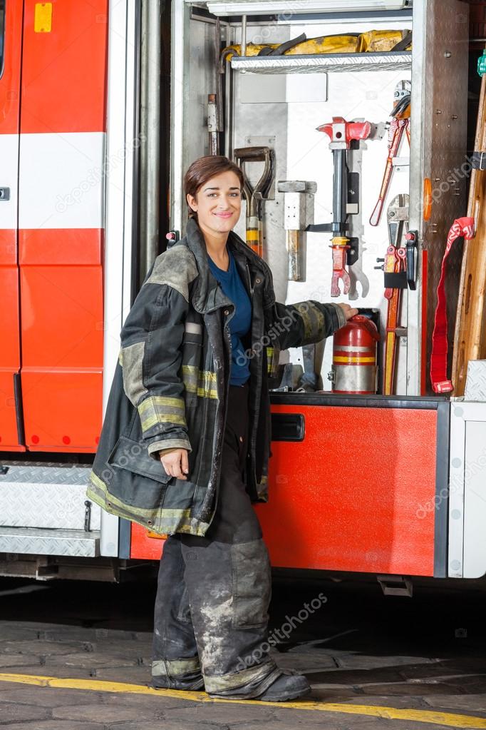 Smiling Firefighter Standing By Truck At Fire Station