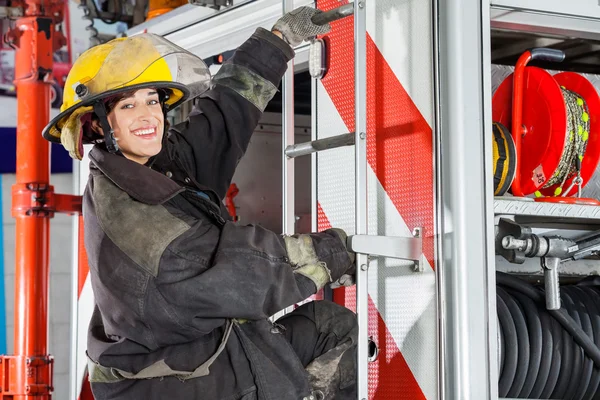 Lächelnder Feuerwehrmann steht auf LKW am Feuerwehrhaus — Stockfoto