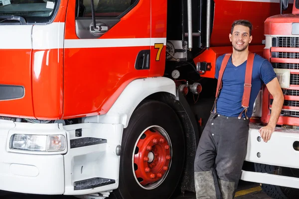 Fiducioso pompiere appoggiato al camion — Foto Stock