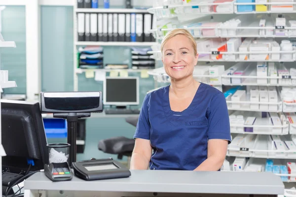 Confident Assistant Sitting At Cash Counter In Pharmacy — Stock Photo, Image