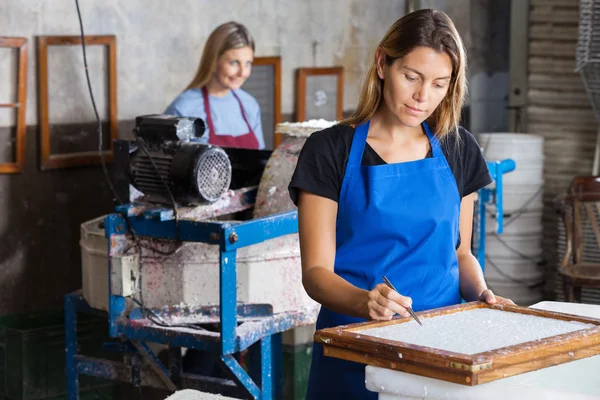 Trabalhadora feminina usando pinças para limpar o papel — Fotografia de Stock
