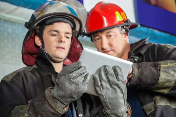 Bomberos masculinos usando tableta digital en la estación de bomberos —  Fotos de Stock