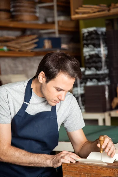 Mid volwassen werknemer met behulp van naald te maken van gaten op papier — Stockfoto