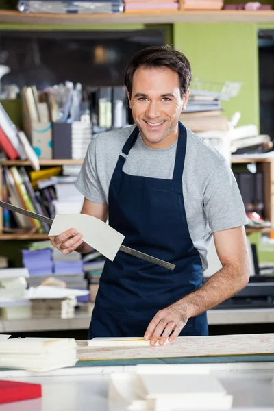 Trabalhador sorridente trabalhando na mesa na indústria de papel — Fotografia de Stock