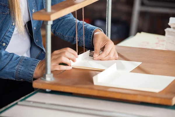 Жінка працівник зв'язування папери на Workbench — стокове фото