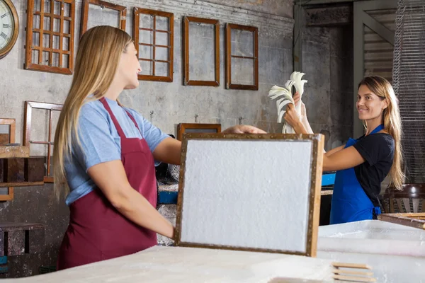 Trabajador sosteniendo el molde con papel mientras mira a su colega — Foto de Stock