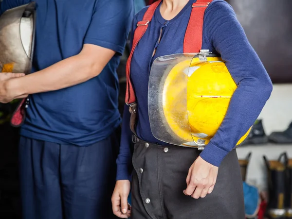 Bombeiros segurando capacetes no quartel de bombeiros — Fotografia de Stock