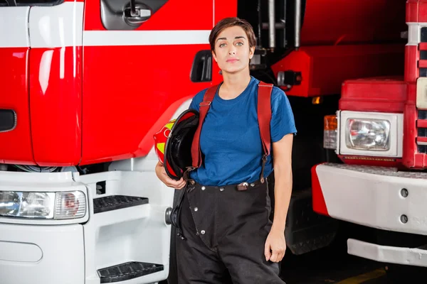 Mulher de fogo confiante segurando capacete contra Firetruck — Fotografia de Stock