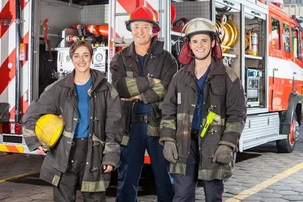 Bomberos felices de pie contra camión — Foto de Stock