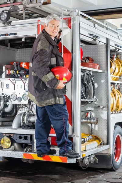 Pompier debout sur camion à la caserne de pompiers — Photo