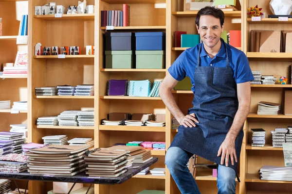 Vendedor adulto medio sentado en la escalera en la librería — Foto de Stock