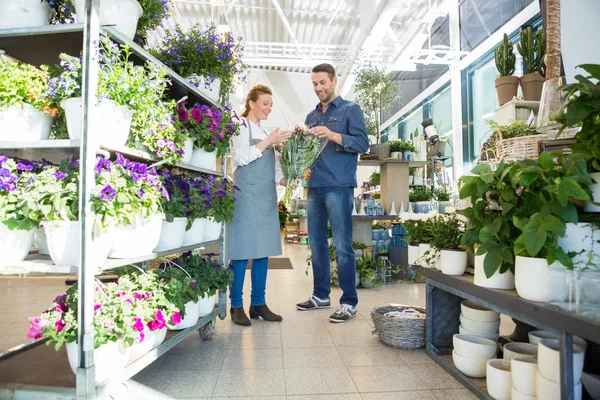 Дівчина-продавець допомагає клієнту купувати букет квітів — стокове фото
