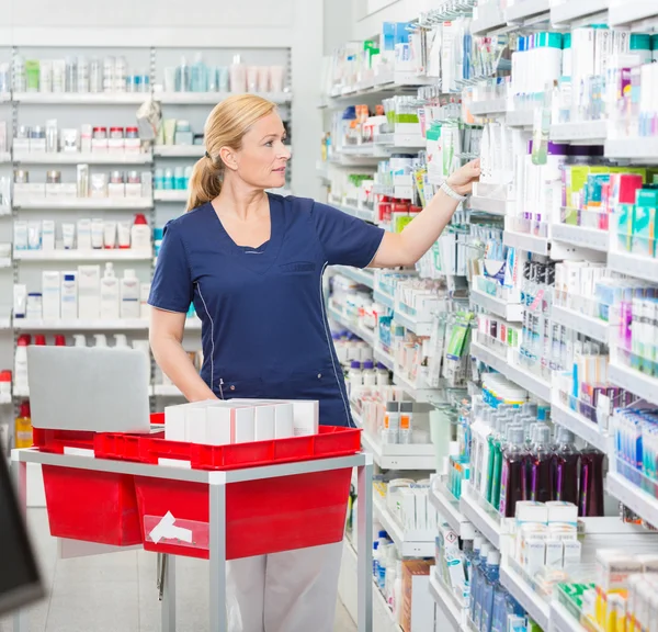 Químico Organizar medicamentos em prateleiras na farmácia — Fotografia de Stock