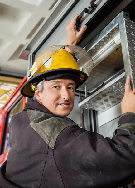 Selbstbewusster Feuerwehrmann klettert auf Lastwagen — Stockfoto