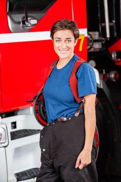 Bombero mujer feliz de pie contra camión de bomberos — Foto de Stock