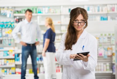 Female Chemist Holding Digital Tablet At Pharmacy clipart