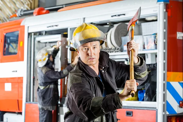 Vertrouwen brandweerman houdt bijl bij brandweerkazerne — Stockfoto