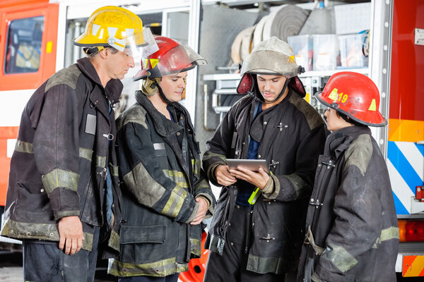 Firefighters Using Tablet Computer At Fire Station