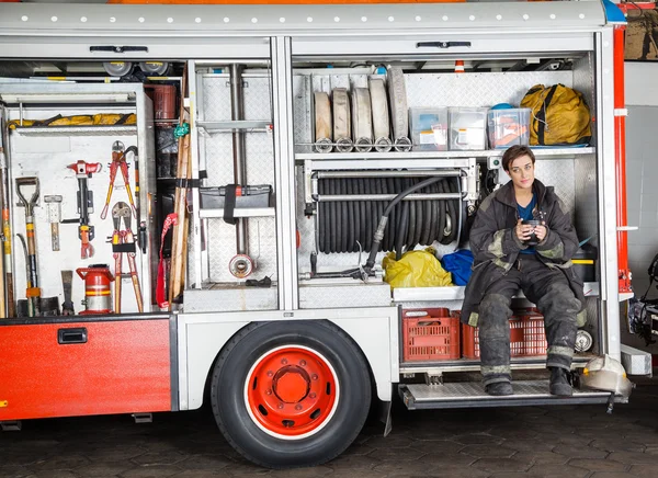 Feuerwehrfrau hält Kaffeebecher in Lastwagen — Stockfoto