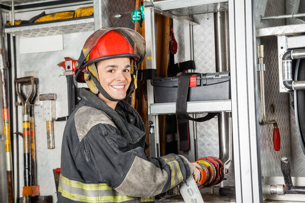 Happy Firefighter Fixing Water Hose In Truck