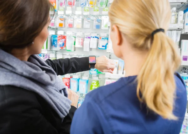 Cliente feminino mostrando Smartwatch ao farmacêutico na farmácia — Fotografia de Stock