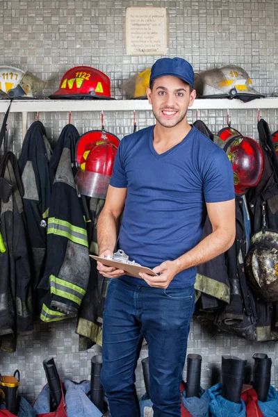 Bombero seguro sosteniendo portapapeles en la estación de bomberos — Foto de Stock