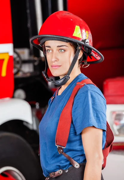 Pewnie Firewoman w czerwony hełm stojące przed Truck — Zdjęcie stockowe