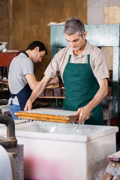 Dělník, namáčení formy ve vodě ve výrobě papíru a buničiny — Stock fotografie