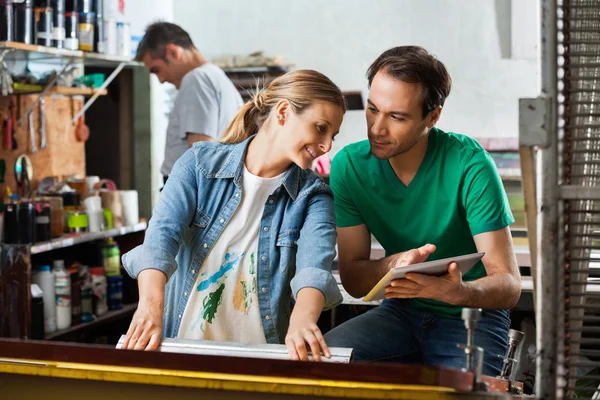 Supervisor que muestra diseño en la tableta digital al empleado usando el cuadrado — Foto de Stock