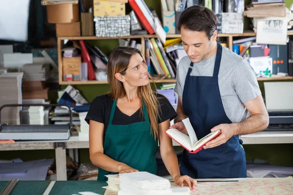 Arbeiter schaut Kollege an, der Buch in Papierfabrik hält — Stockfoto